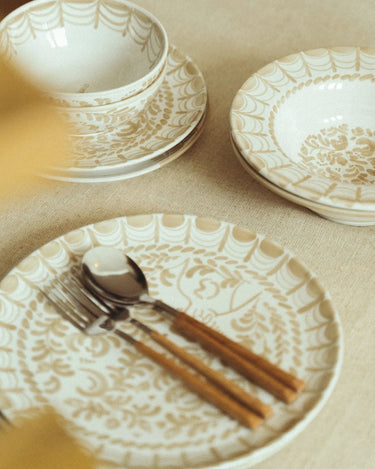 Plato de Leandro Cano: mesa con plato llano en primer plano y vajilla de la misma decoración.