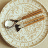 Plato llano de gres con arcos pintados en beige de Leandro Cano: plato llano con arcos beige y cubiertos con mangos de madera.