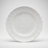 Plato llano de gres blanco con relieves de arcos de Leandro Cano: plato llano blanco apoyado de pie, con arcos y motivos vegetales en relieve.