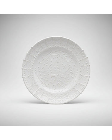 Plato de Leandro Cano: plato llano blanco de pie en composición más amplia sobre fondo gris.