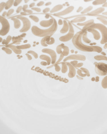 Plato de postre de gres con decoración beige lateral de Leandro Cano: detalle de motivos beige y firma Leandro Cano en plato de postre.