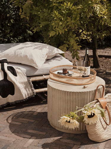 Podio beige de Broste Copenhagen junto a una tumbona de exterior