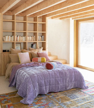 Polochón Hanky Izamal de lino lavado en beige mostaza de Le Monde Sauvage, sobre una cama en un dormitorio de madera