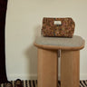 Puf Lazare en madera natural de Gabrielle Paris, en vestidor con bolso