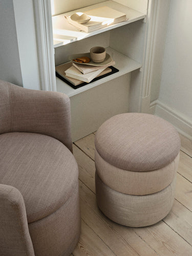 Puf pequeño beige de Broste Copenhagen junto a un sillón