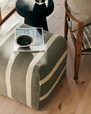 Puf verde agave y beige junto a una mesa auxiliar