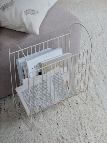 Revistero de hierro gris claro de Broste Copenhagen junto a un sofá
