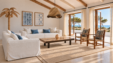 Salón abierto al mar con sofás de lino blanco, mesa Roger Capron, sillones vintage y textiles azules. Imagen de inspiración generada con IA.