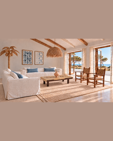 Salón junto al mar con mesa marrón de Roger Capron con azulejos botánicos, jarrón V.III de Marta Bonilla, cojines Lane azules y sofás blancos.