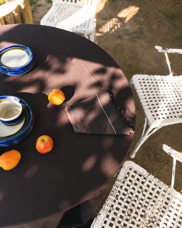 Servilletas de algodón café en una mesa con vajilla azul y fruta