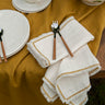 Detalle de las servilletas de algodón natural con zigzag mostaza y flecos de Bicla en una mesa puesta