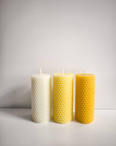 Tres velas de cera de abeja blanca y amarilla vistas de frente