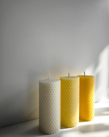 Velas de cera de abeja blanca y amarilla iluminadas lateralmente