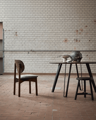 Silla de roble oscuro junto a una mesa y una pared de azulejos
