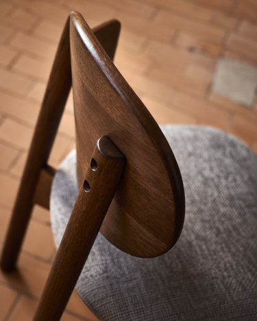 Detalle del respaldo curvo oscuro y el tejido gris del asiento