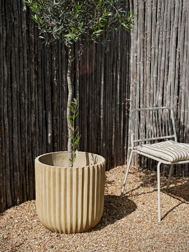 Detalle de la silla beige gris frente a una valla de madera