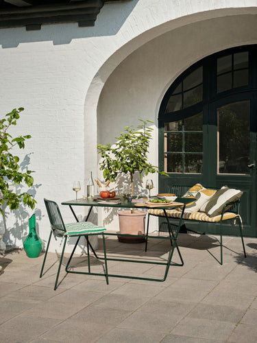 Silla verde bosque en una terraza con mobiliario a juego