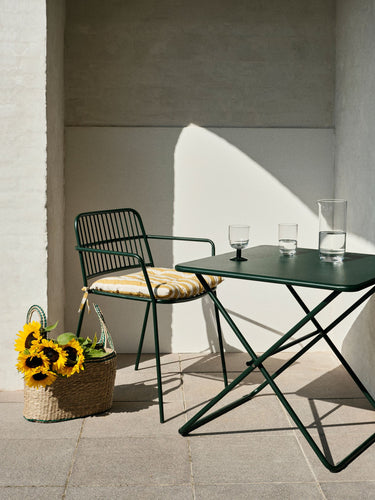 Silla verde bosque con reposabrazos en una terraza soleada
