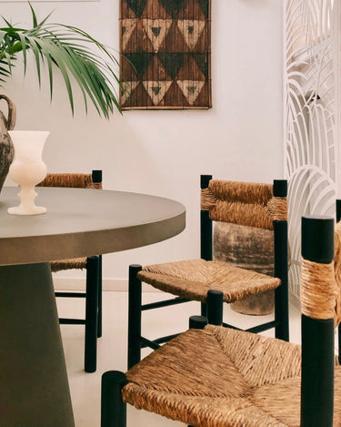 Sillas vintage de madera oscura y fibra trenzada junto a una mesa