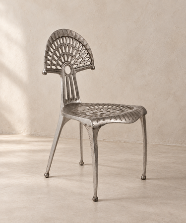 Silla Urogallo de aluminio vintage, vista en tres cuartos sobre suelo de cemento beige