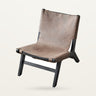 Sillón de cuero marrón y madera negra de MUUBS, visto en tres cuartos