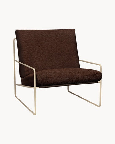 Sillón de Ferm Living con cojines marrones y estructura beige, visto de tres cuartos.