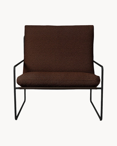 Sillón de Ferm Living con cojines marrones y estructura negra, vista frontal.