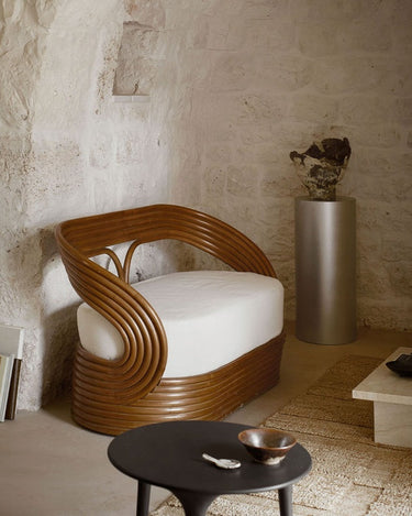 Sillón Mandola de ratán color caramelo con cojín blanco en un salón