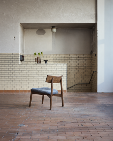 Sillón Tetra oscuro ante una pared de azulejos claros