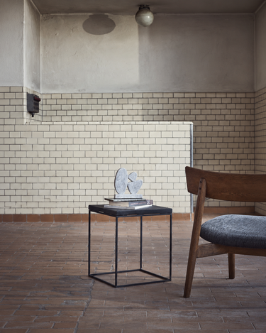 Sillón de roble oscuro acompañado de una pequeña mesa auxiliar