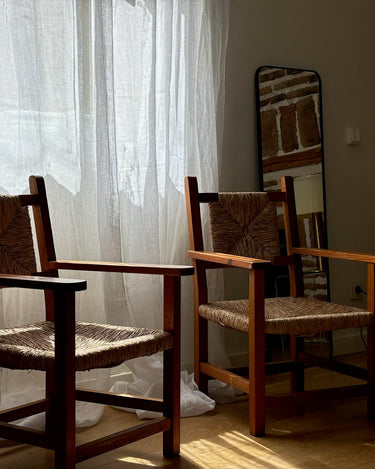 Pareja de sillones de madera y asiento trenzado junto a una ventana