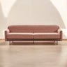 Sofá rosa con brazos de madera en un salón de paredes claras