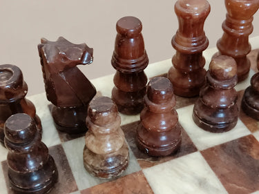 Detalle de figuras marrones de ajedrez sobre el tablero veteado.
