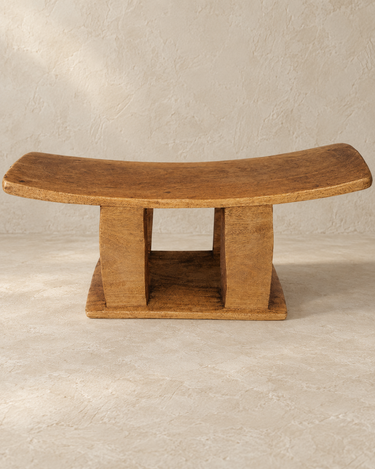 Vista frontal del apoyacuellos africano, con asiento curvo y base de madera tallada