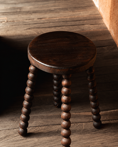 Taburete de madera de mango oscura, vista oblicua sobre suelo de madera