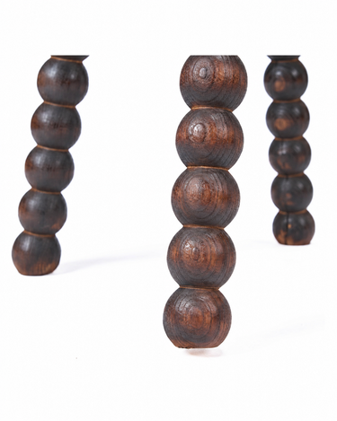 Taburete de madera de mango oscura, detalle de los segmentos redondeados de las patas