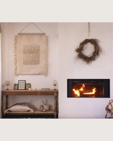 Tapiz de pared crudo con lana y flecos de Bed and Philosophy, en una pared junto a una chimenea