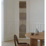 Tapiz de pared de lana y lino con flecos largos de Linie Design: colgado junto a una mesa y una silla.