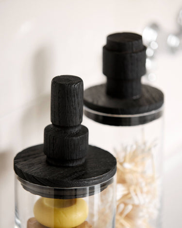 Tarro de vidrio con tapa de pino negro y contenido