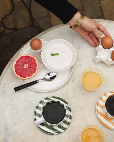 Hand-painted green stoneware cup by Olsson & Jensen on a table