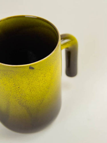 Taza de cerámica esmaltada presentada sobre una mesa natural