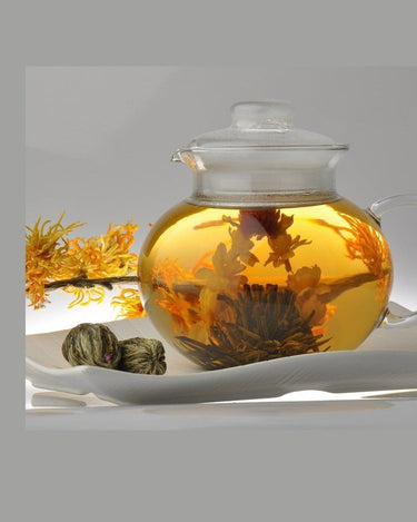 Té floreciente abierto en tetera de cristal