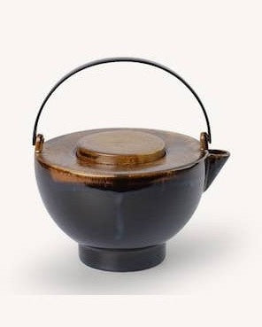 Ambiente natural con tetera de cerámica marrón flameada con asa de latón como protagonista