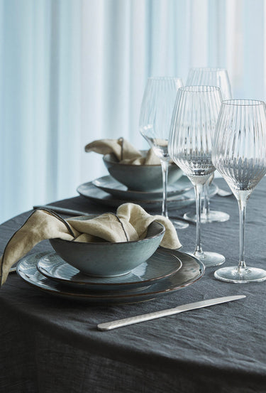 Vajilla de gres azul suave para dos en una mesa con flores