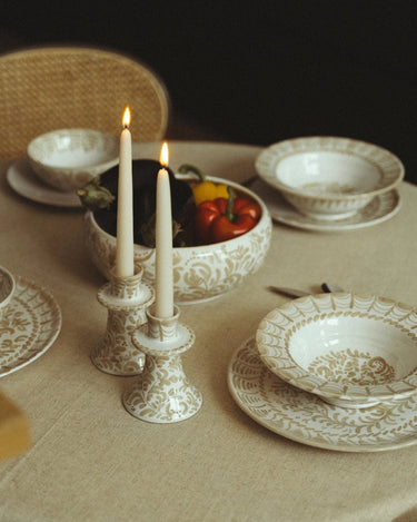 Vajilla de Leandro Cano: mesa con vajilla pintada, candelabros y cuenco con hortalizas.