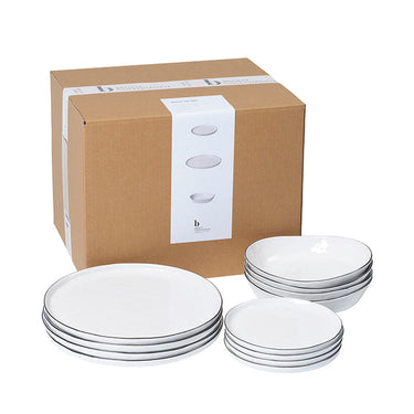 Vajilla blanca con borde negro para cuatro dispuesta sobre una mesa