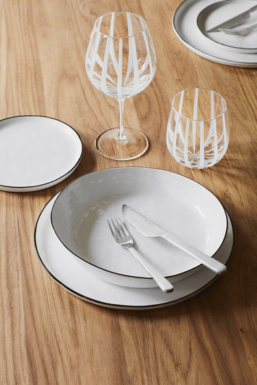 Vajilla blanca con borde negro para cuatro en una composición de mesa