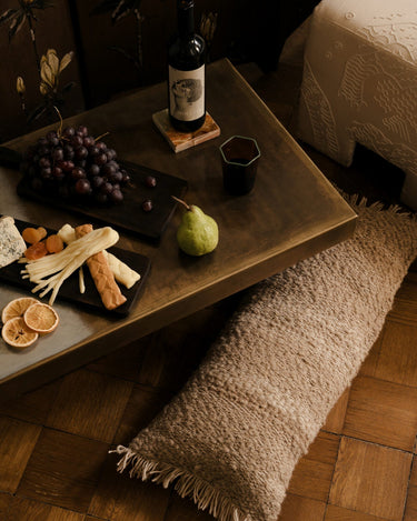 Vaso ámbar con bebida en una mesa junto a vino y fruta