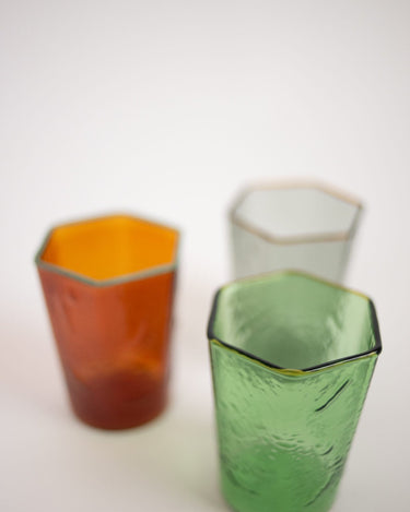 Vaso ámbar desenfocado junto a vasos verde y gris