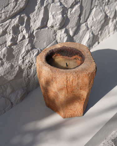 Vela recargable de tronco de madera natural, vista desde arriba junto a una pared de piedra